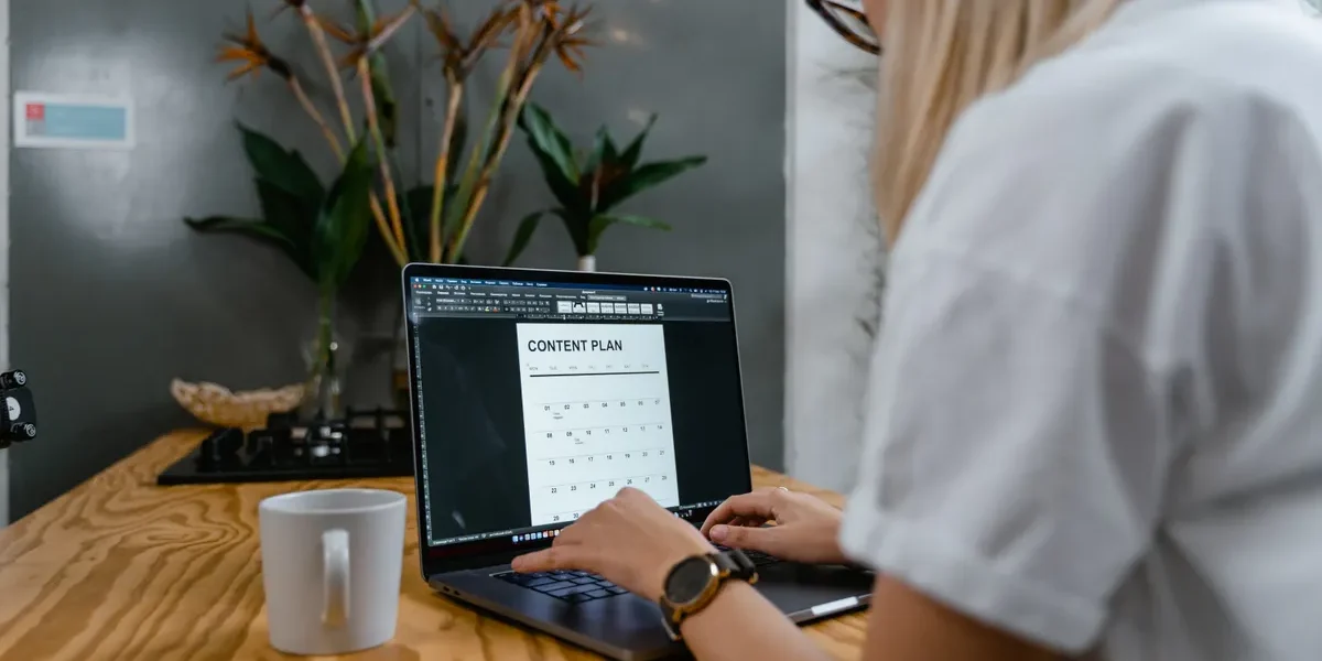 Person using laptop with a content plan on screen